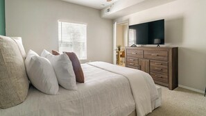 A bedroom with a bed, a dresser, a television, and a window with blinds. - Landing | Stunning 1BD, Gym, Clubhouse (Houston)