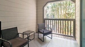 Ein Balkon mit Stuhl und kleinem Tisch, Holzwände und Blick auf Bäume.