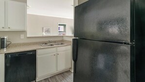 A kitchen with a black refrigerator, white cabinets, a dishwasher, and a granite countertop. - Landing | Amazing 2BD, Gym, Clubhouse (Houston)