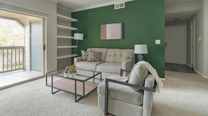 A living room with a green accent wall, a sofa, a chair, a coffee table, and a lamp. - Landing | Beautiful 2BD, Clubhouse, Gym (Houston)