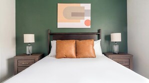 Ein Hotelzimmer mit einem Einzelbett, zwei Nachttischen und einem an der Wand hängenden Kunstwerk.