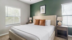 A bedroom with a large bed, two nightstands, a framed picture on the wall, and two windows with blinds. - Landing | Stunning 2BD, Clubhouse, Gym (Houston)