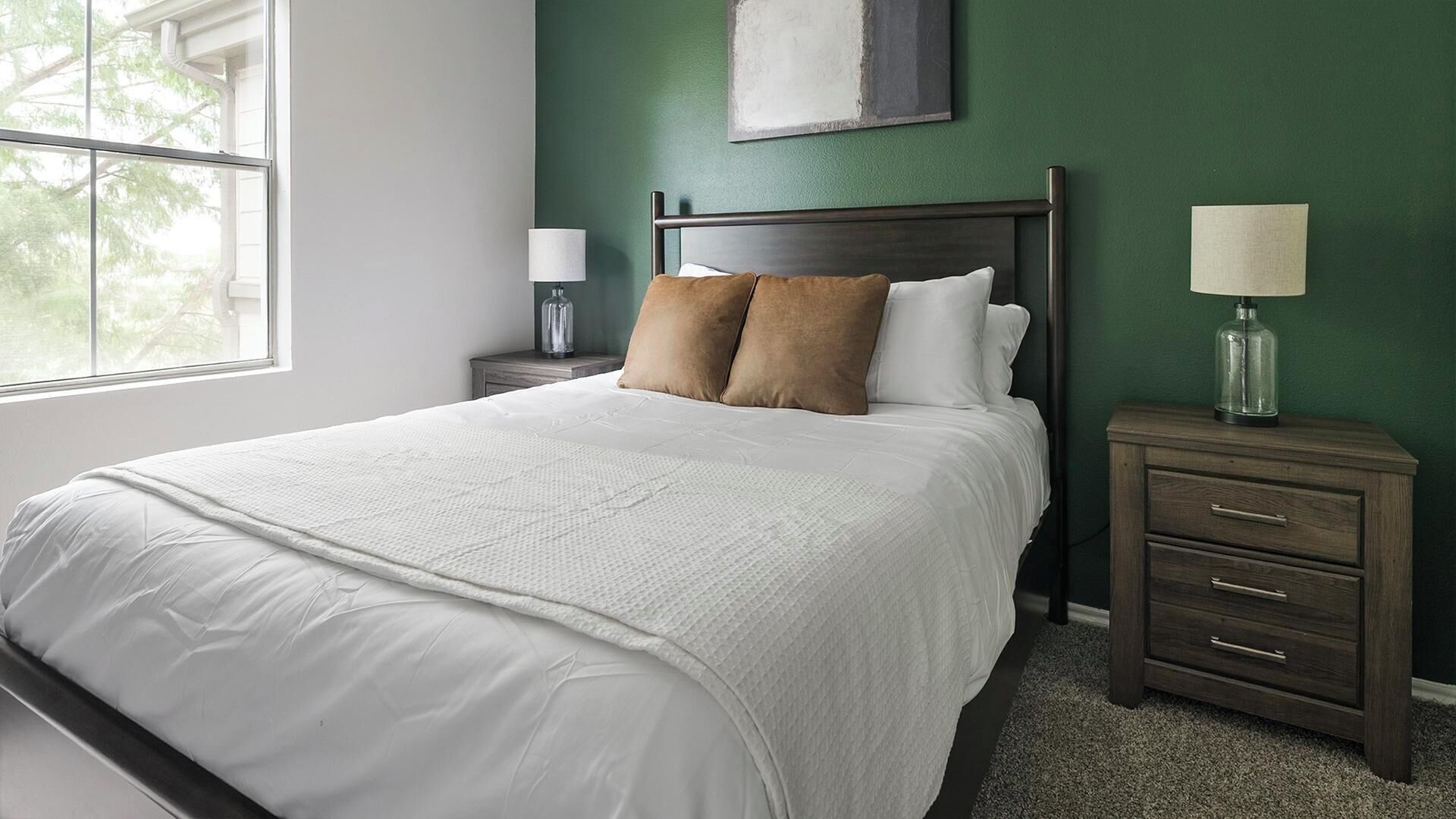 A bedroom with a large bed, two nightstands, a dresser, and a window.