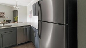 Eine moderne Küche mit Edelstahlgeräten, einem Geschirrspüler und einem zweitürigen Kühlschrank.