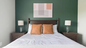 A neatly made bed with two pillows, a wooden headboard, and two bedside tables with lamps. - Landing | Incredible 3BD, Gym, Clubhouse (Houston)