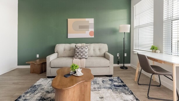 A living room with a sofa, coffee table, and a desk with a chair. - Landing | Modern 1BD, Game Room, Gym (Punta Gorda)