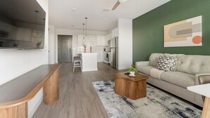 A modern living space with a kitchen, dining area, and a sofa. - Landing | Modern 1BD, Game Room, Gym (Punta Gorda)