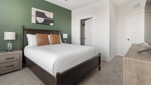 A bedroom with a bed, bedside tables, a wardrobe, and a door leading to another room. - Landing | Modern 1BD, Game Room, Gym (Punta Gorda)