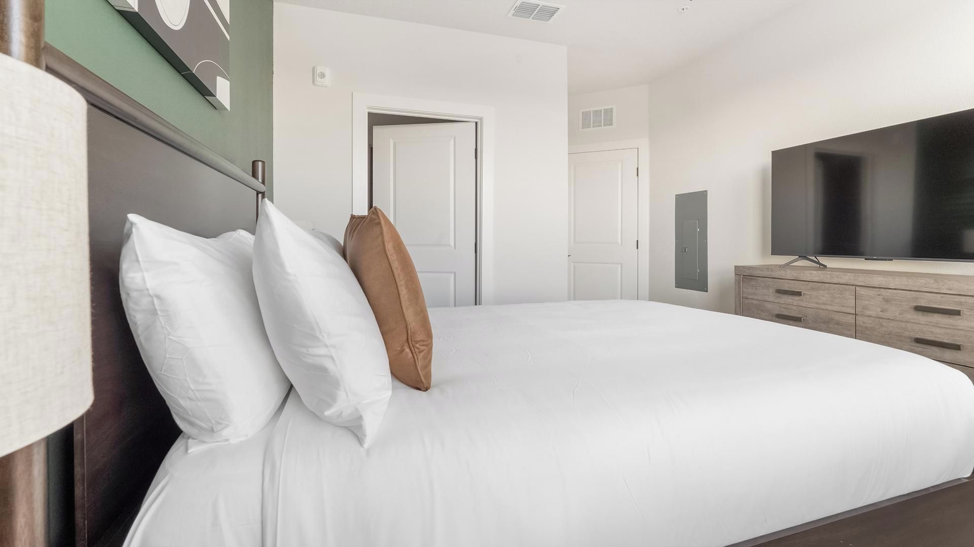 Une chambre d’hôtel avec un grand lit, une télévision et une armoire.