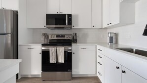 A modern kitchen with white cabinetry, stainless steel appliances, and a built-in oven. - Landing | Spectacular 1BD, Yoga Studio, Game Room (Punta Gorda)