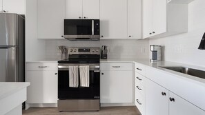A modern kitchen with white cabinetry, stainless steel appliances, and a built-in oven. - Landing | Spectacular 1BD, Yoga Studio, Game Room (Punta Gorda)