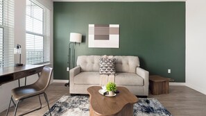 A modern living room with a sofa, coffee table, and a lamp. - Landing | Spectacular 1BD, Yoga Studio, Game Room (Punta Gorda)