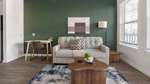 A modern living room with a sofa, a coffee table, a desk, and a lamp. - Landing | Amazing 1BD, Gym, Game Room (Punta Gorda)