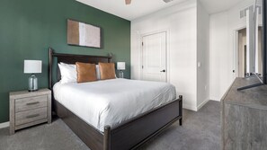 Ein Schlafzimmer mit einem Bett, Nachttischen, einer Kommode und einer Tür.