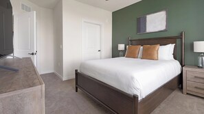 A bedroom with a bed, nightstands, a dresser, and a door. - Landing | Amazing 1BD, Gym, Game Room (Punta Gorda)