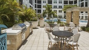 Zona de piscina en la azotea con mobiliario exterior y una parrilla.