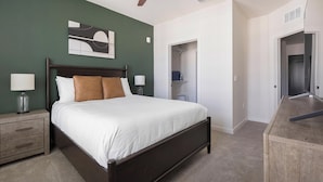 Un dormitorio con cama, mesitas de noche, un cuadro en la pared y un vestidor.