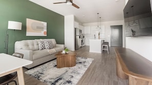 A modern living room with a sofa, coffee table, and a kitchen in the background.