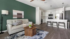 A modern living room with a sofa, coffee table, and a rug. - Landing | Beautiful 1BD, Yoga Studio, Gym (Punta Gorda)