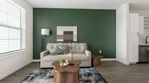 A living room with a green accent wall, a grey sofa, a wooden coffee table, and a modern lamp. - Landing | Stunning 1BD, Yoga Studio, Gym (Punta Gorda)
