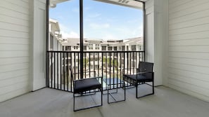A balcony with a view of a residential area, featuring a black metal railing and two black chairs. - Landing | Stunning 1BD, Yoga Studio, Gym (Punta Gorda)