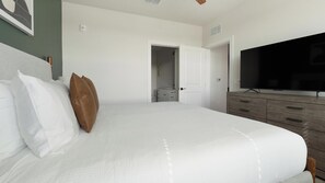 A bedroom with a bed, a television, a wardrobe, and a door leading to a bathroom. - Landing | Spectacular 2BD, Game Room, Yoga Studio (Punta Gorda)