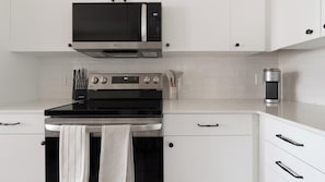A modern kitchen with stainless steel appliances, including a microwave, oven, and coffee maker. - Landing | Spectacular 2BD, Game Room, Yoga Studio (Punta Gorda)