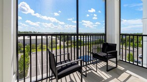 A balcony with a view of a parking lot and buildings. - Landing | Spectacular 2BD, Game Room, Yoga Studio (Punta Gorda)