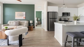 A modern living room with a sofa, a coffee table, and a dining area with bar stools. - Landing | Amazing 2BD, Yoga Studio, Game Room (Punta Gorda)