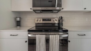 A modern kitchen with a stainless steel stove, oven, and microwave. There are two ovens, a coffee maker, and a knife block on the counter. - Landing | Spectacular 2BD, Gym, Game Room (Punta Gorda)