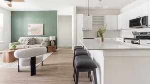 Um apartamento moderno com sala de estar, cozinha e balcão de refeições.