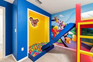 Ein Spielbereich für Kinder mit Rutsche, Bällebad und Wanddekorationen.