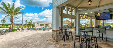 A covered outdoor area with a pool, bar, and seating.