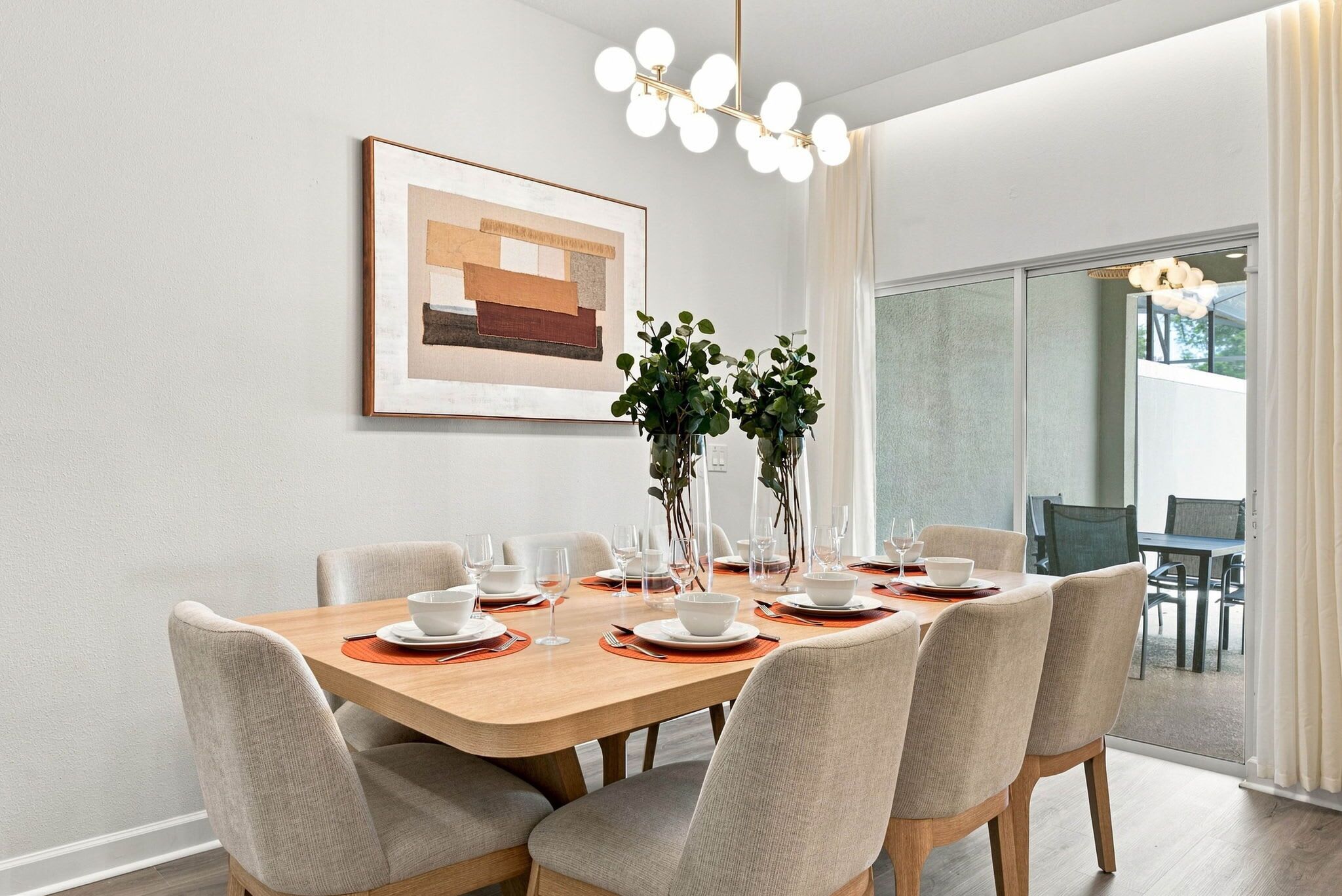 Een eetruimte met een houten tafel, gedekt voor zes personen, omringd door gestoffeerde stoelen.