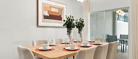 Un coin repas avec une table en bois dressée pour six personnes, entourée de chaises rembourrées.