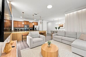 Ein modernes Wohnzimmer mit einer Couch, einem Couchtisch und einer Küche im Hintergrund.