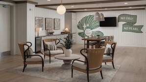 A spacious living room with a dining area, featuring a large wall mural, a flat-screen TV, and a modern chandelier. - Landing | Stylish 2BD, Gym, Clubhouse (Port Charlotte)