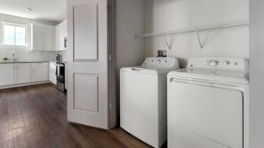 Vaskerum med to hvide vaskemaskiner, en tørretumbler og en metalkasse øverst.