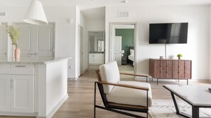 A modern living space with a kitchen, dining area, and a TV mounted on the wall. - Landing | Incredible 2BD, Clubhouse, Pool (Port Charlotte)