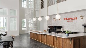 Ett modernt kök med en köksö i mitten, en kaffemaskin och en skylt med texten ”TRAPEZE COFFEE”.