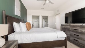 Ein Hotelzimmer mit einem Bett, einem Schminktisch, einem Fernseher und einem Deckenventilator.