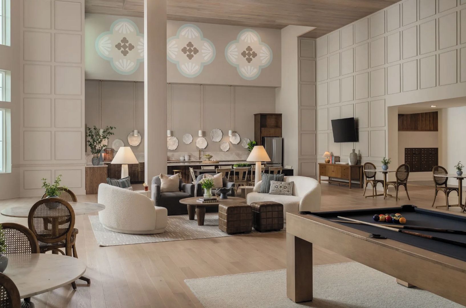 A spacious living area with a pool table, comfortable seating, and a kitchen in the background.