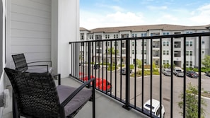 Ein Balkon mit Blick auf einen Parkplatz und ein Mehrfamilienhaus.