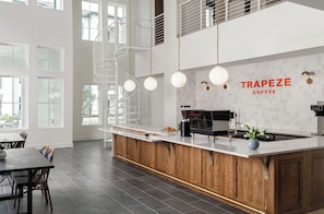 Eine moderne Küche mit einer zentralen Kochinsel, einer Kaffeemaschine und einem Schild mit der Aufschrift 'TRAPEZE COFFEE'.