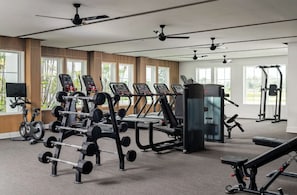 Een moderne sportschool met diverse fitnessapparaten, grote ramen en plafondventilatoren.