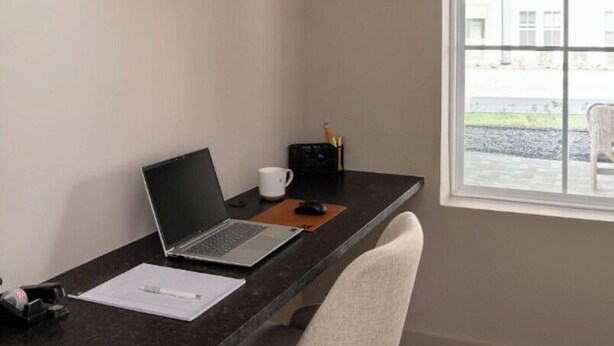 Un espacio de trabajo con una computadora portátil, una taza de café y una lámpara de escritorio.