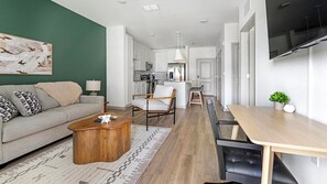 Ein modernes Wohnzimmer mit einer Couch, einem Couchtisch und einem Essbereich mit Tisch und Stühlen.