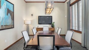 A conference room with a long table, chairs, a flat-screen TV, and a painting of horses. - Landing | Stunning 2BD, Pool, Gym (Austin)