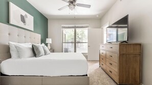 Ein Schlafzimmer mit einem Bett, einem Holzkapfen, einem Fernseher, einem Deckenventilator und einem Fenster mit Jalousien.