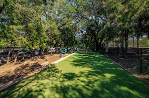 A park with a green pathway, trees, and a fence. - Landing | Stylish 2BD, Gym, Pool (Austin)